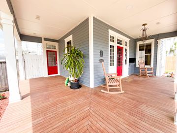 Bay City house for rent - A wooden rocking chair is on a porch with a red door.