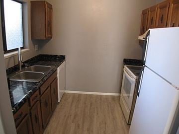 Grand Junction apartment for rent - A kitchen with a white fridge, black countertops, and wooden cabinets.