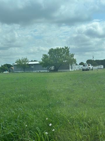 Clyde house for rent - A grassy field with a house and trees in the background.