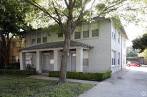 Dallas apartment for rent - A tree in front of a two-story building.