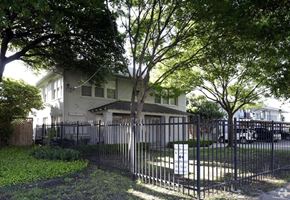 Dallas apartment for rent - A house with a black fence and a tree in front.