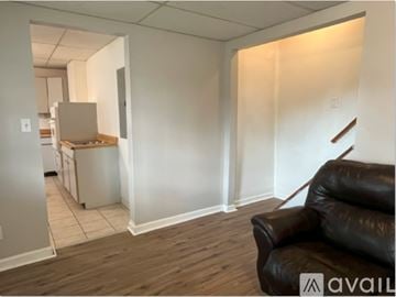 West Carrollton apartment for rent - A living room with a black leather couch and a kitchen in the background.