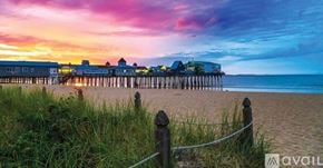Old Orchard Beach townhouse for rent - A beach scene with a pier and buildings in the distance during sunset.