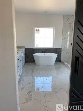 Fort Gibson house for rent - A bathroom with a white tub and marble flooring.
