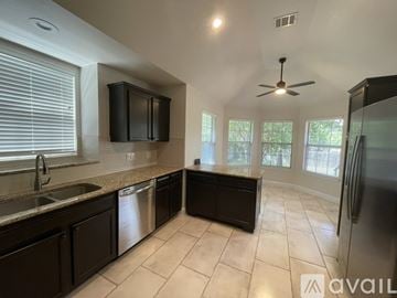 Pflugerville house for rent - A kitchen with black cabinets and a stainless steel refrigerator.