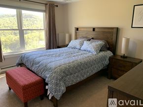 Thornton house for rent - A bedroom with a large bed and a window overlooking a green landscape.