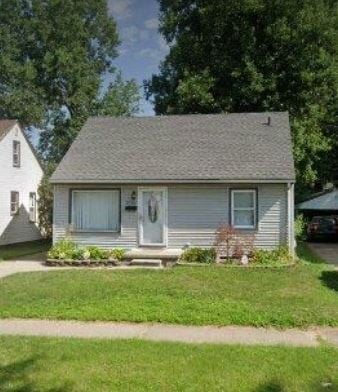 Dearborn Heights house for rent - A small house with a grey roof and white siding is surrounded by greenery.
