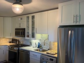 Takoma Park house for rent - A kitchen with white cabinets and a stainless steel refrigerator.