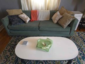 Trinidad apartment for rent - A green couch with pillows and a white coffee table in front of it.