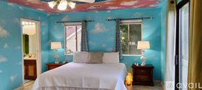 Benicia house for rent - A bedroom with a blue wall and a wooden dresser with a mirror on top.