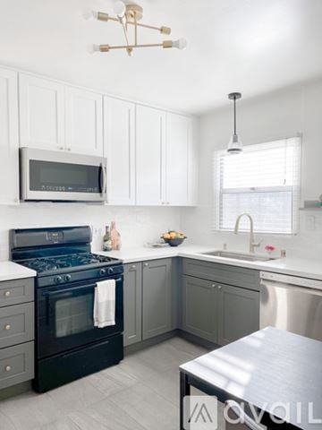 San Diego house for rent - A modern kitchen with a black stove top oven and white cabinets.
