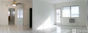 Surfside apartment for rent - A spacious room with a ceiling fan and a window with blinds.