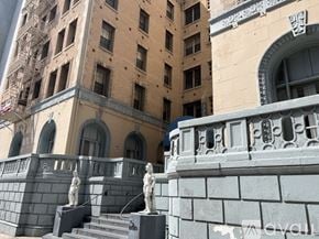 Los Angeles apartment for rent - A building with a grey railing and two statues on the steps.