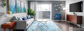 San Antonio apartment for rent - A living room with a grey couch, a blue chair, a wooden side table, a rug, and a television.