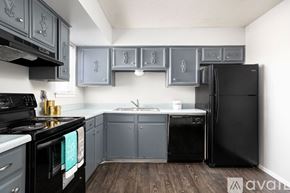 San Antonio apartment for rent - A kitchen with black appliances and grey cabinets.