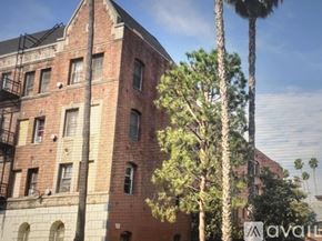 Los Angeles apartment for rent - A tall red brick building with a balcony on the second floor.