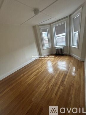 Boston apartment for rent - A room with wooden floors and three windows.
