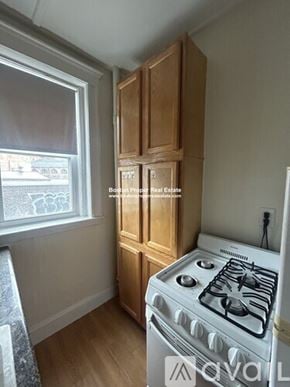Boston apartment for rent - A small kitchen with a white stove and wooden cabinets.