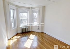 Boston apartment for rent - A room with wooden floors and white walls, with a window and a radiator.