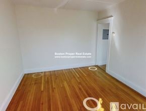 Boston apartment for rent - A room with wooden flooring and white walls, with a doorway leading to another room.