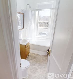 Boston apartment for rent - A white bathroom with a toilet, sink, and window.