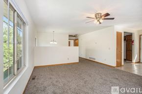 Kalamazoo house for rent - A spacious room with a ceiling fan and a carpeted floor.