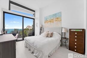 Miami apartment for rent - A bedroom with a large bed and a view of the ocean through a sliding glass door.