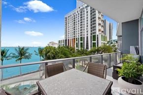 Miami apartment for rent - A balcony with a table and chairs overlooks a pool and a view of the ocean.