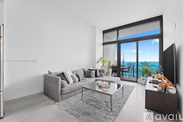 Miami apartment for rent - A modern living room with a grey sofa and a glass table.