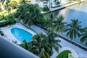 Miami apartment for rent - A pool surrounded by palm trees and a waterfront view.