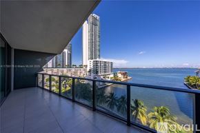 Miami apartment for rent - A balcony overlooks a cityscape with tall buildings and a body of water.