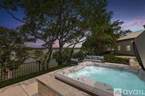 Gainesville house for rent - A hot tub is surrounded by a concrete patio and a black fence with trees in the background.