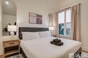 Houston townhouse for rent - A bedroom with a large bed, a nightstand with a lamp, and a framed picture on the wall.