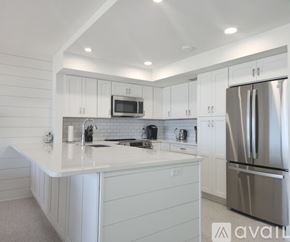 Longboat Key condo for rent - A modern kitchen with white cabinets and a stainless steel refrigerator.