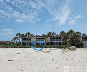 Longboat Key condo for rent - A blue circle is on a sandy beach in front of a building.