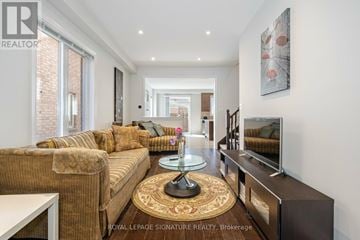 Mississauga (Churchill Meadows) house for rent - A living room with a brown couch and a glass coffee table.