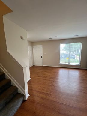 Capitol Heights house for rent - A room with wooden floors and a staircase leading to another room.