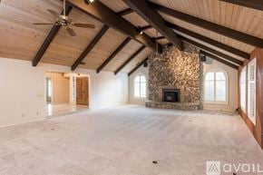 Fresno apartment for rent - A spacious room with a stone fireplace and wooden beams on the ceiling.