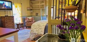 Lake Lure house for rent - A living room with a TV, a couch, a chair, a table, a vase with purple flowers, and a shelf with a bowl on it.