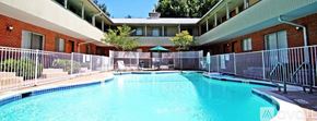 Dallas apartment for rent - A swimming pool surrounded by a fence and a building in the background.