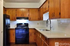 Dallas apartment for rent - A kitchen with wooden cabinets and a black fridge.