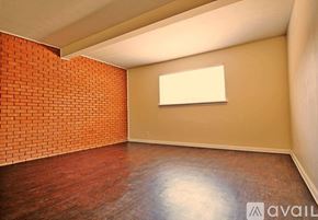 Dallas apartment for rent - A room with a brick wall and wooden floor.