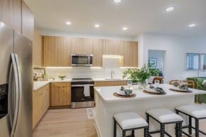 Birmingham apartment for rent - A modern kitchen with a refrigerator, microwave, oven, and a dining table set for two.