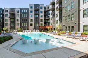 Birmingham apartment for rent - A swimming pool surrounded by lounge chairs in front of apartment buildings.