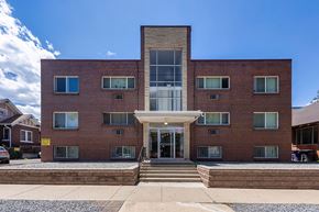 Denver apartment for rent - A red brick building with a white entrance and a glass window.