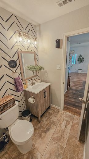 Killeen house for rent - A bathroom with a toilet, sink, and mirror.