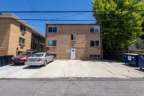 Denver apartment for rent - A red car is parked in front of a brick building.