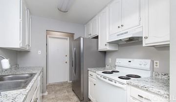 Temple house for rent - A kitchen with white cabinets and a granite countertop.