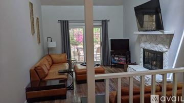Raleigh house for rent - A living room with a brown leather couch and a television on a stand.