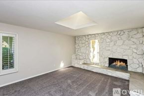 Chino house for rent - A living room with a stone fireplace and a grey carpet.